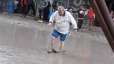 رجل يحمل أطفال المدارس على كتفه من طين الأمطار بالإسكندرية.. 